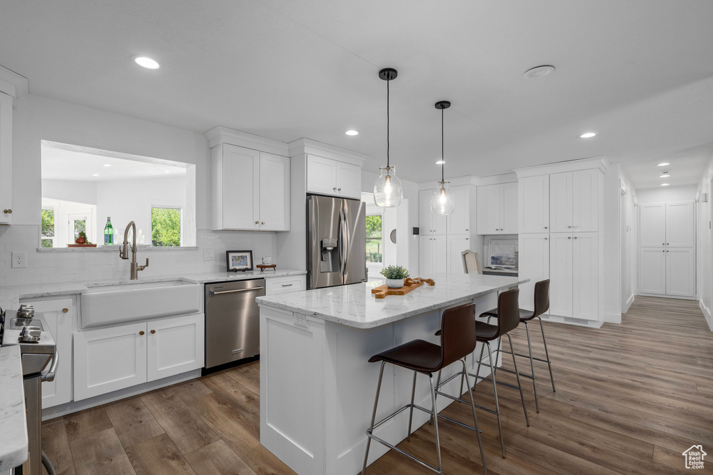 Kitchen with appliances with stainless steel finishes, white cabinets, dark hardwood / wood-style floors, sink, and tasteful backsplash