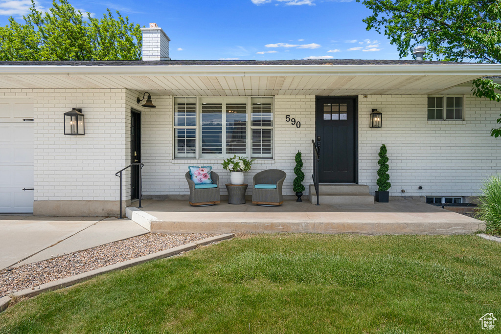 Entrance to property with a garage, a yard, and a porch