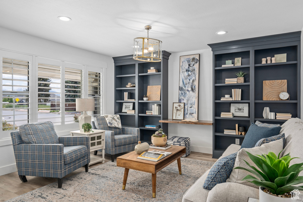 Living room with built in shelves, a chandelier, and wood-type flooring