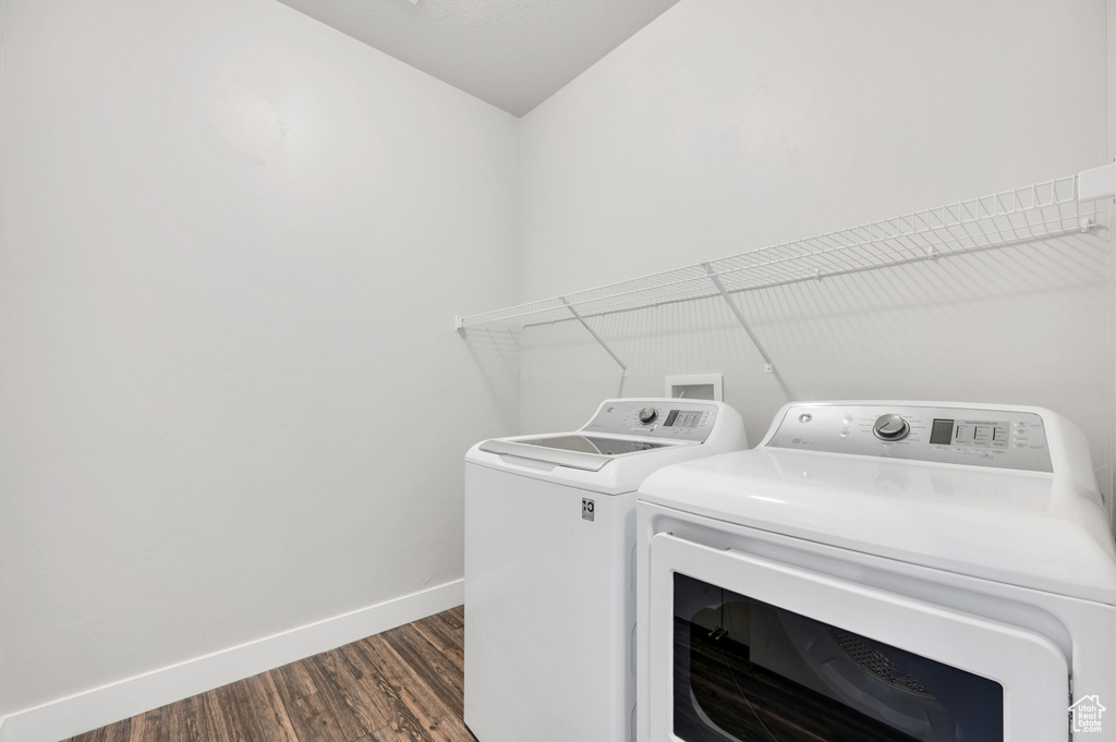 Clothes washing area with washer and dryer, dark wood-type flooring, and washer hookup