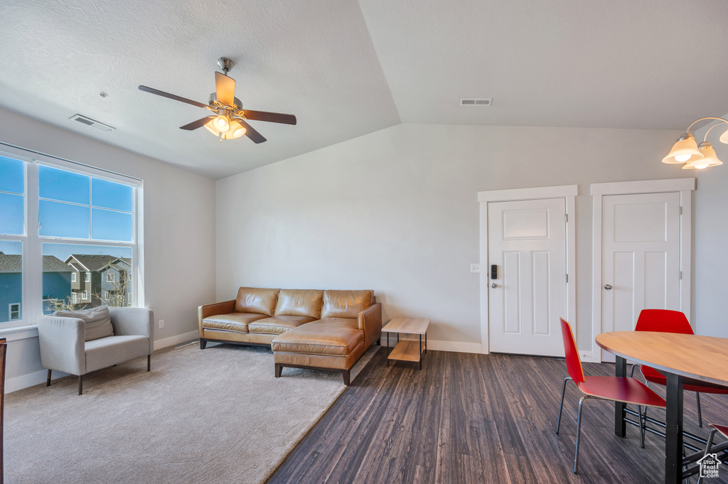 Living room featuring dark wood-type flooring, ceiling fan, and vaulted ceiling