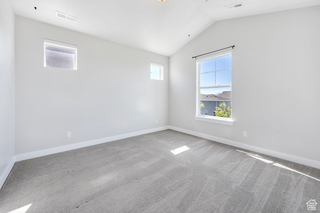 Carpeted spare room with vaulted ceiling