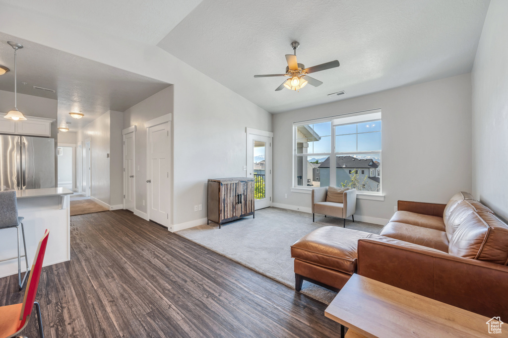 Living room featuring ceiling fan, vaulted ceiling, and dark wood-type flooring