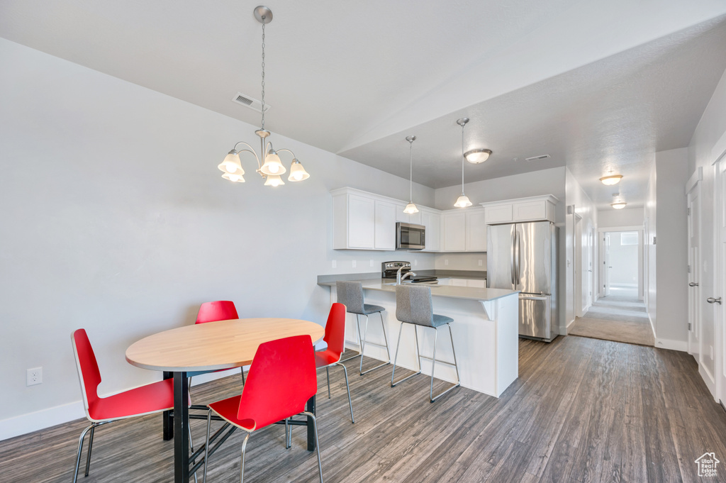 Dining area with an inviting chandelier, lofted ceiling, and hardwood / wood-style floors