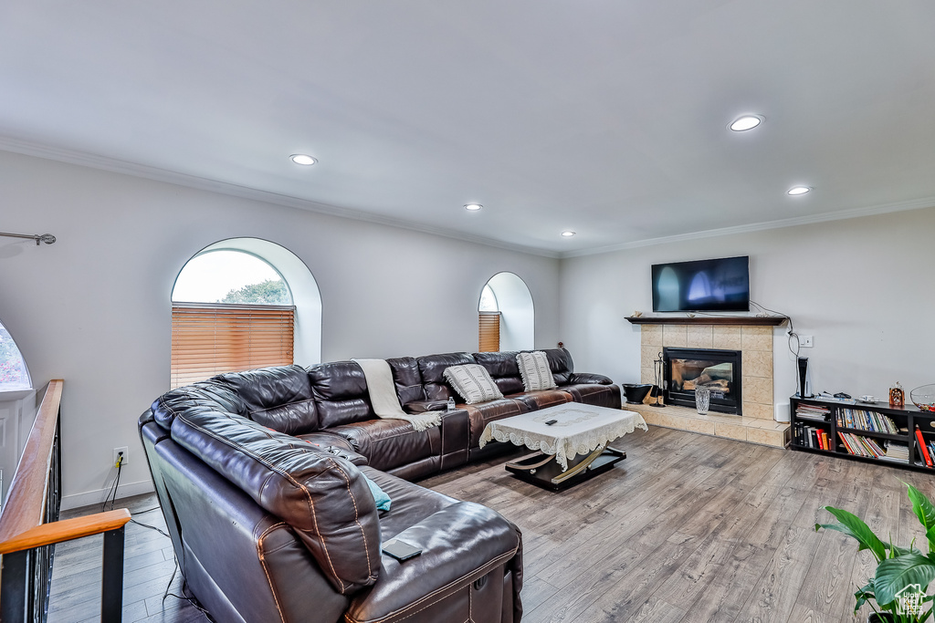 Living room featuring ornamental molding, a tiled fireplace, and hardwood / wood-style floors