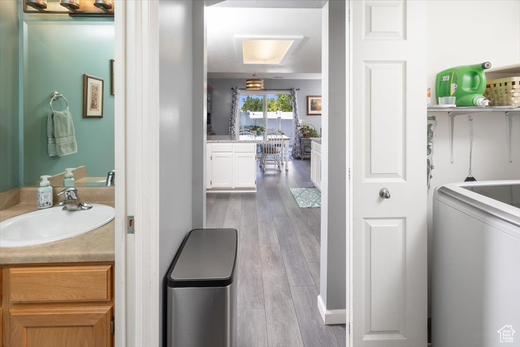 Bathroom with ornamental molding, wood-type flooring, washer / clothes dryer, and oversized vanity