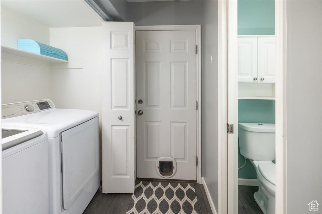 Clothes washing area with dark hardwood / wood-style floors and washing machine and clothes dryer