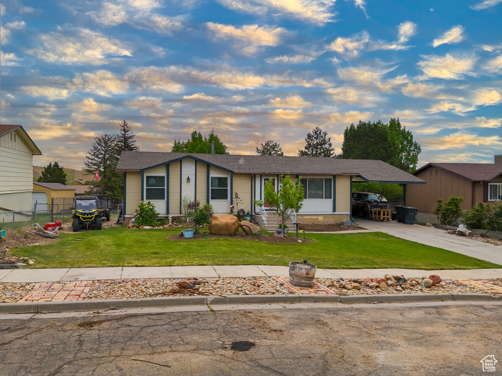 Ranch-style home featuring a carport and a yard