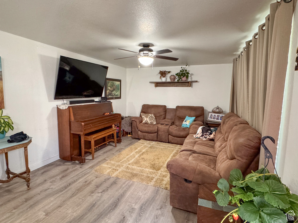 Living room with hardwood / wood-style floors, ceiling fan, and a textured ceiling