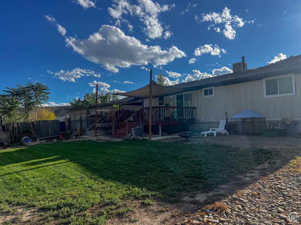 Rear view of property with a deck and a lawn