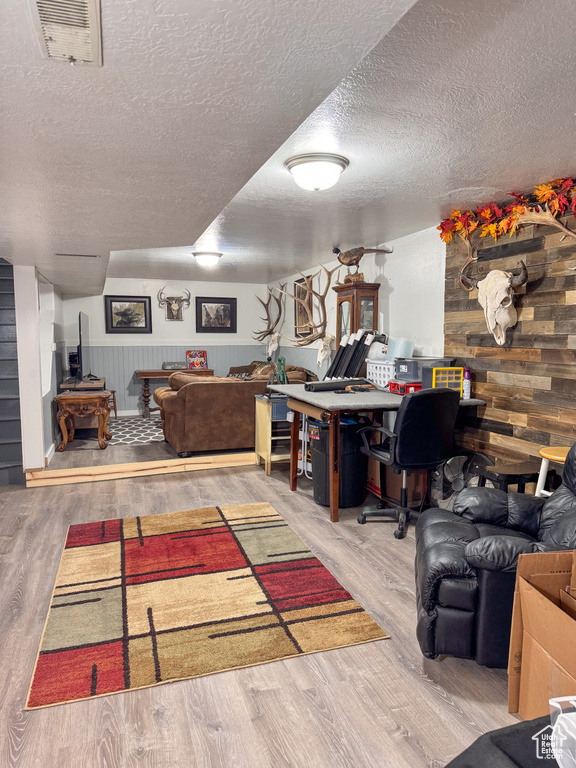 Living room featuring hardwood / wood-style flooring, wooden walls, and a textured ceiling