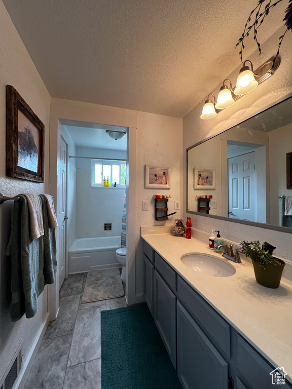 Full bathroom with a textured ceiling, tile flooring, vanity with extensive cabinet space, shower / bath combination with curtain, and toilet