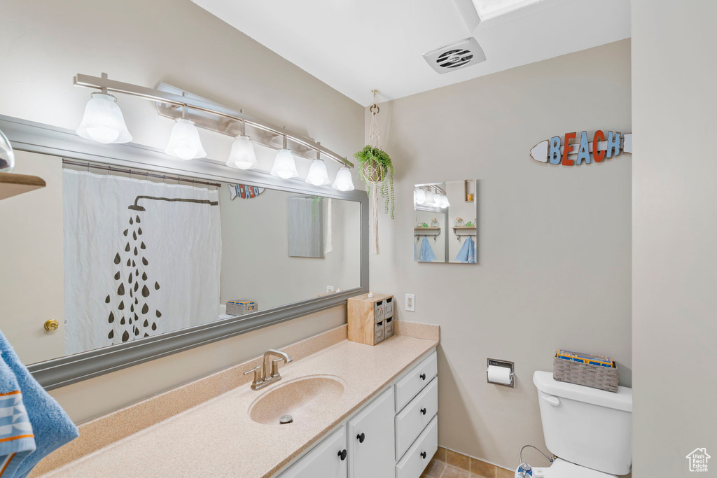 Bathroom with large vanity, tile floors, and toilet