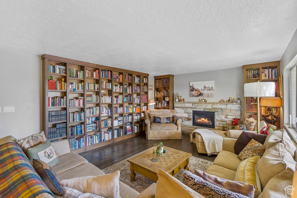 Living room with wood-type flooring, a fireplace, and a textured ceiling