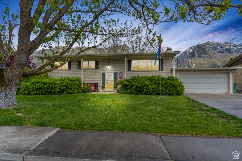 Split foyer home featuring a garage, a mountain view, and a lawn