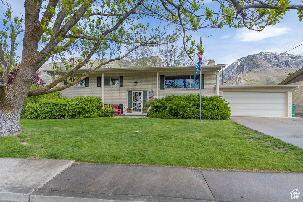 View of front of house with a mountain view, a garage, and a front yard