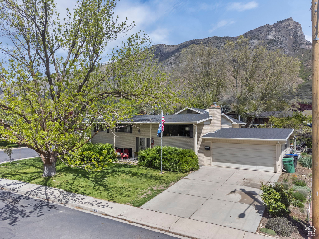 View of front of house featuring a front lawn, a garage, and a mountain view