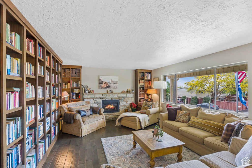 Living room with dark wood-type flooring, a textured ceiling, and a fireplace