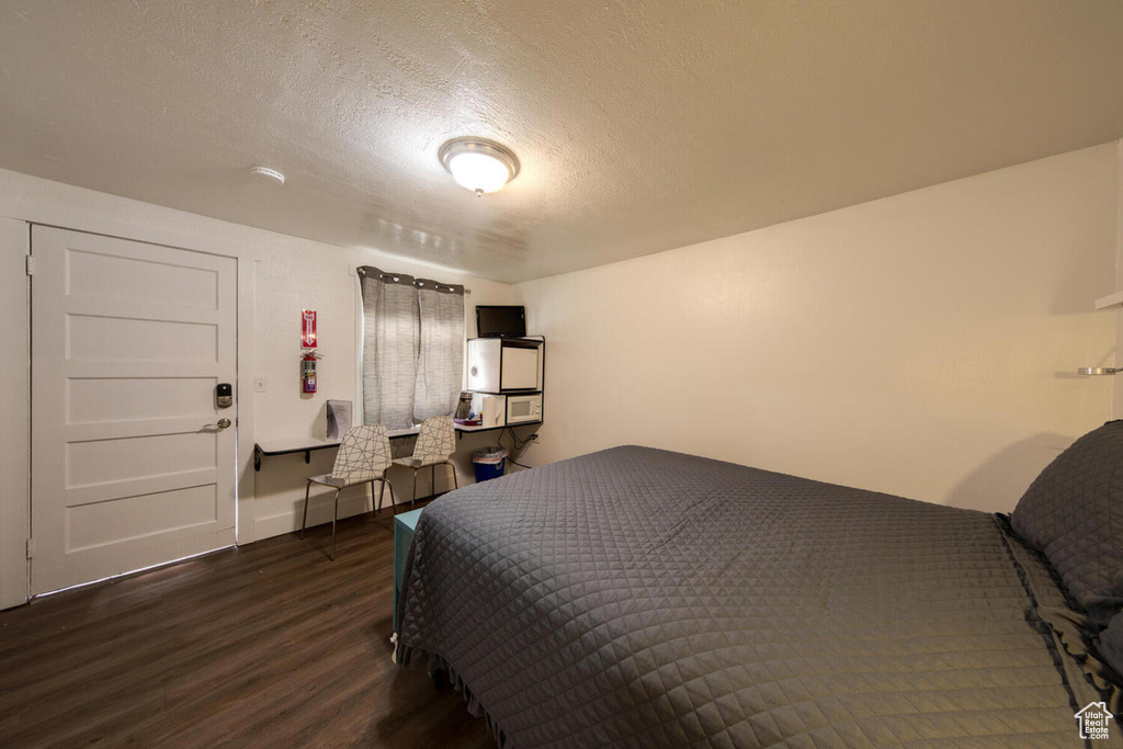 Bedroom with a textured ceiling and dark wood-type flooring