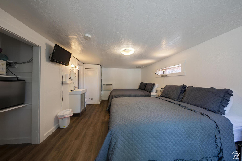 Bedroom featuring dark hardwood / wood-style flooring, an AC wall unit, and a textured ceiling