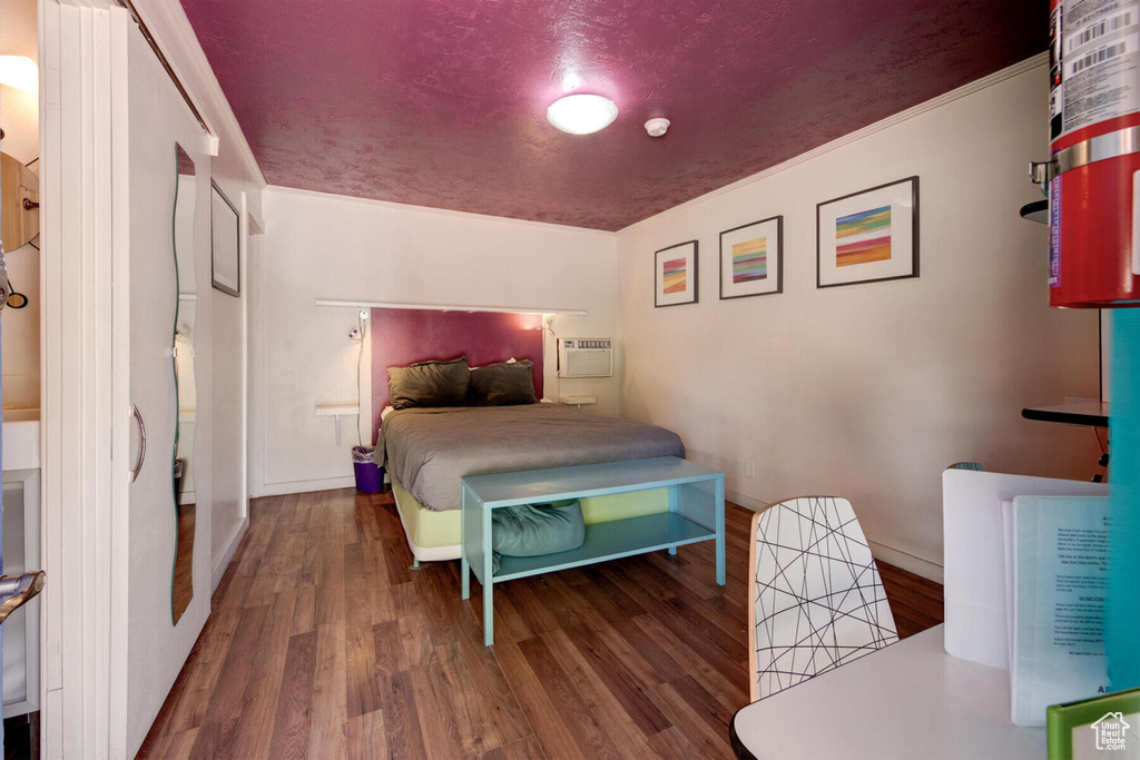 Bedroom with wood-type flooring and a wall mounted air conditioner