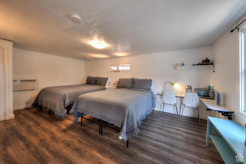 Bedroom featuring dark hardwood / wood-style flooring and a wall mounted air conditioner