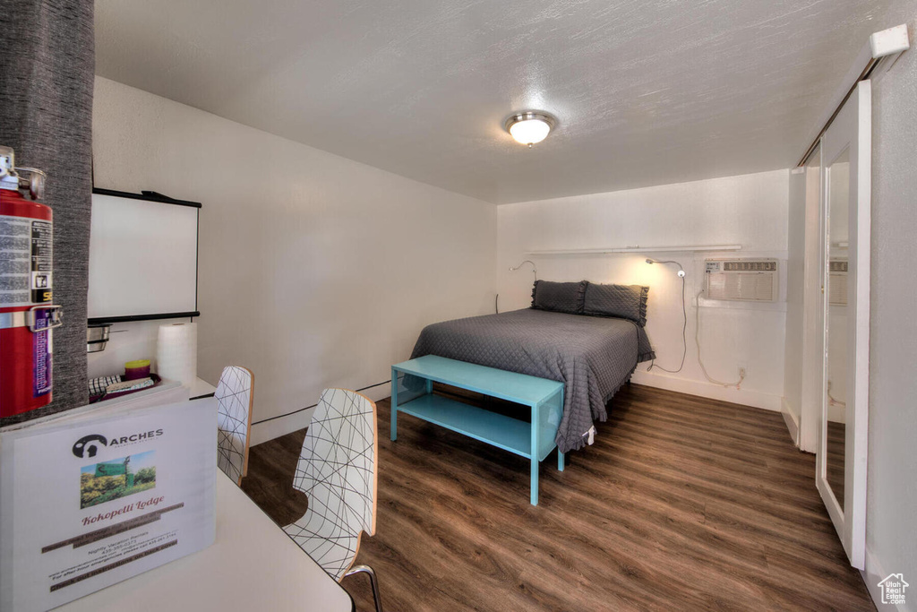 Bedroom featuring a wall mounted AC, a textured ceiling, and dark wood-type flooring