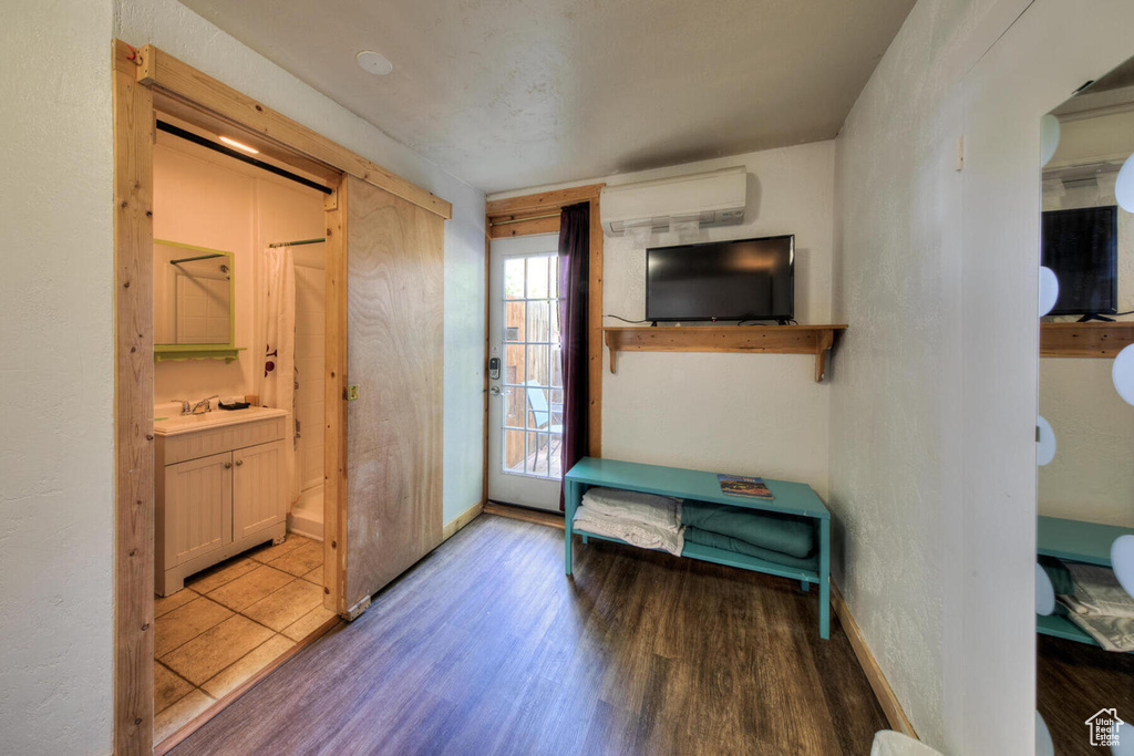 Foyer with sink, dark wood-type flooring, and a wall unit AC