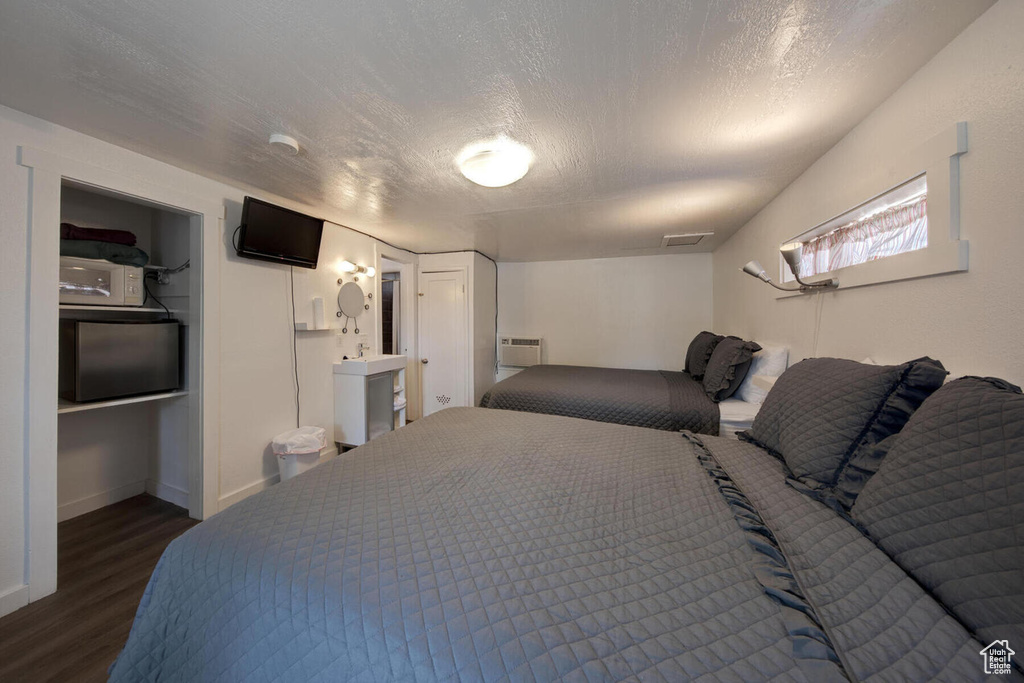 Bedroom with a textured ceiling and dark hardwood / wood-style floors