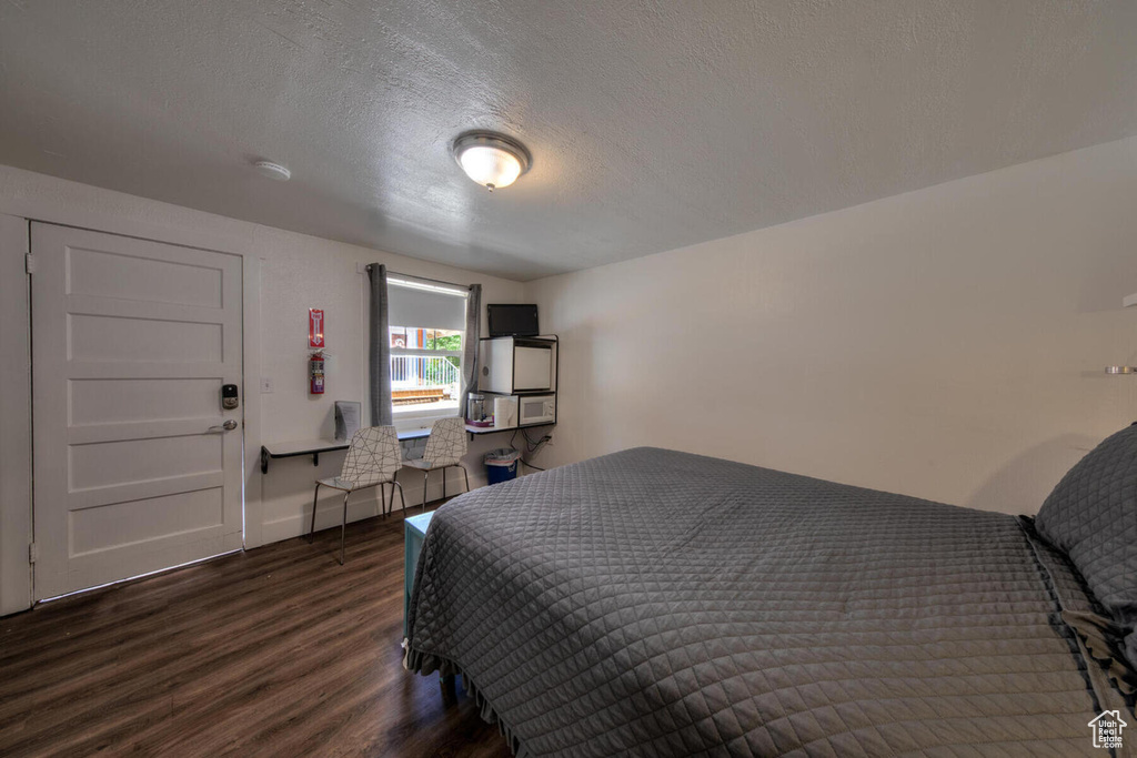 Bedroom with dark hardwood / wood-style flooring and a textured ceiling