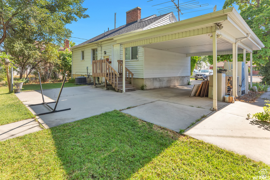 Rear view of property featuring central AC and a yard