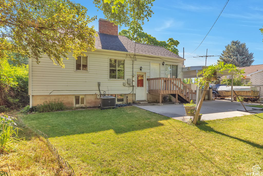 Rear view of property with a lawn and central air condition unit