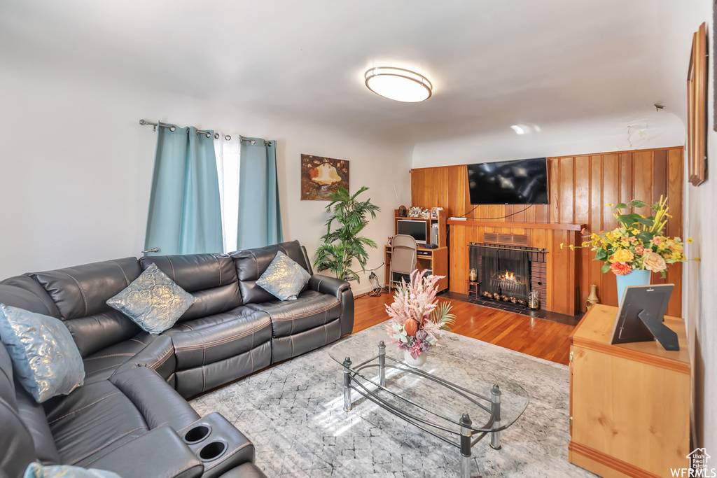 Living room featuring wooden walls, a fireplace, and hardwood / wood-style flooring