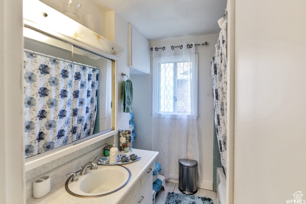 Bathroom with shower / bathtub combination with curtain, large vanity, and tile floors