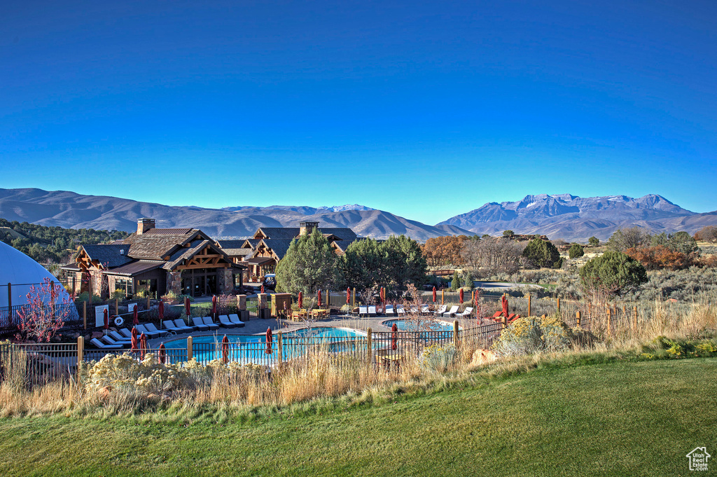 View of pool featuring a mountain view, a lawn, and a patio area