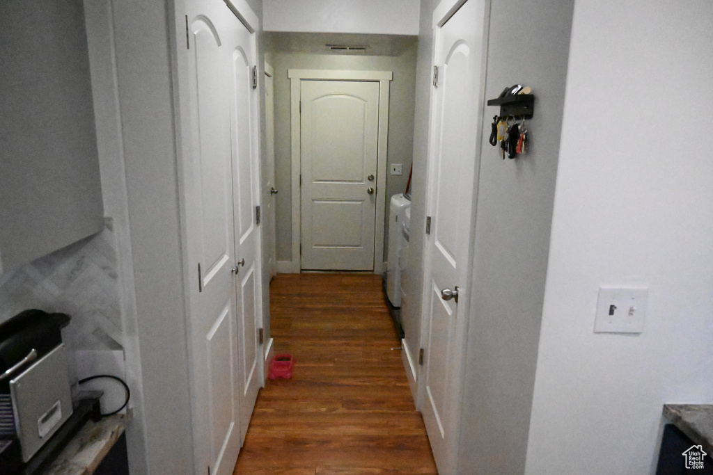 Corridor with washer and dryer and dark hardwood / wood-style flooring