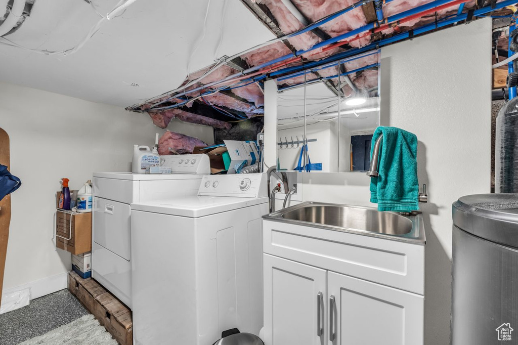 Washroom with sink, washing machine and clothes dryer, and cabinets