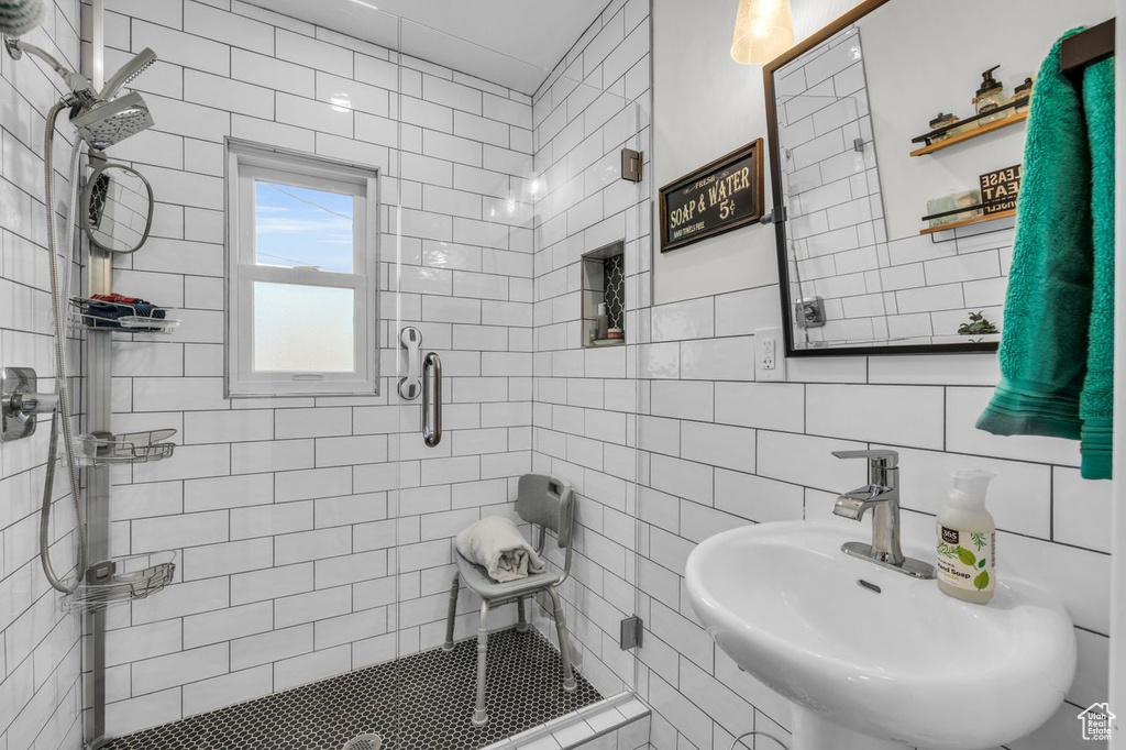 Bathroom featuring sink, an enclosed shower, and tile walls