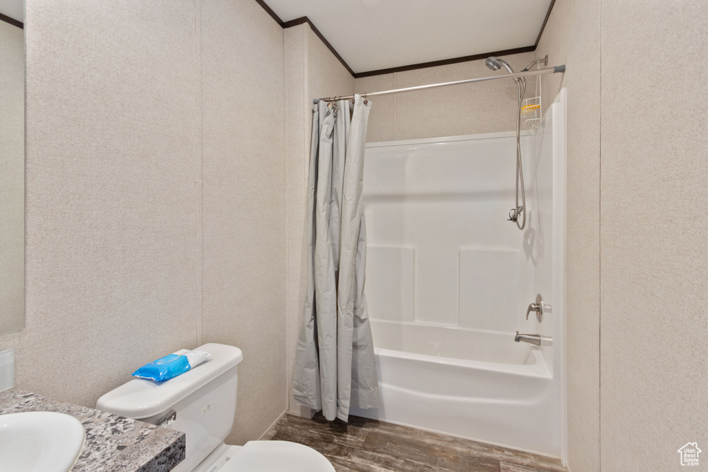 Full bathroom with toilet, sink, hardwood / wood-style floors, and shower / bathtub combination with curtain