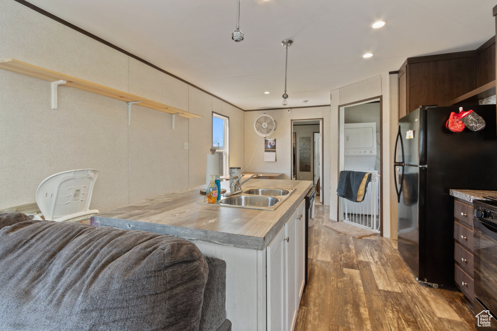 Kitchen with black fridge, hardwood / wood-style flooring, dark brown cabinets, decorative light fixtures, and sink