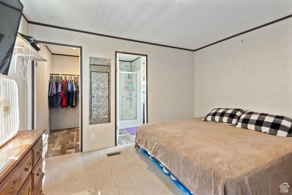 Bedroom featuring a closet, a walk in closet, ornamental molding, wood-type flooring, and connected bathroom