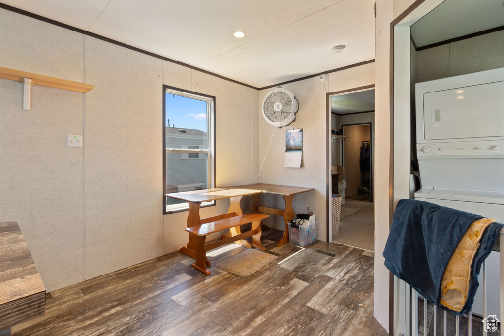 Interior space featuring stacked washer and clothes dryer and dark wood-type flooring