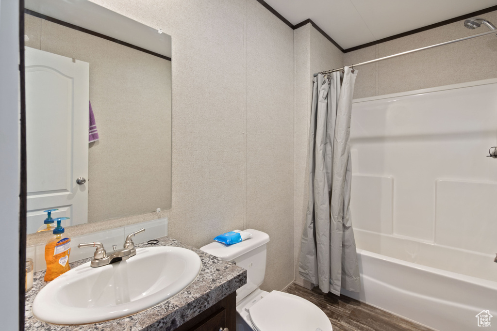 Full bathroom featuring hardwood / wood-style floors, vanity, toilet, and shower / tub combo