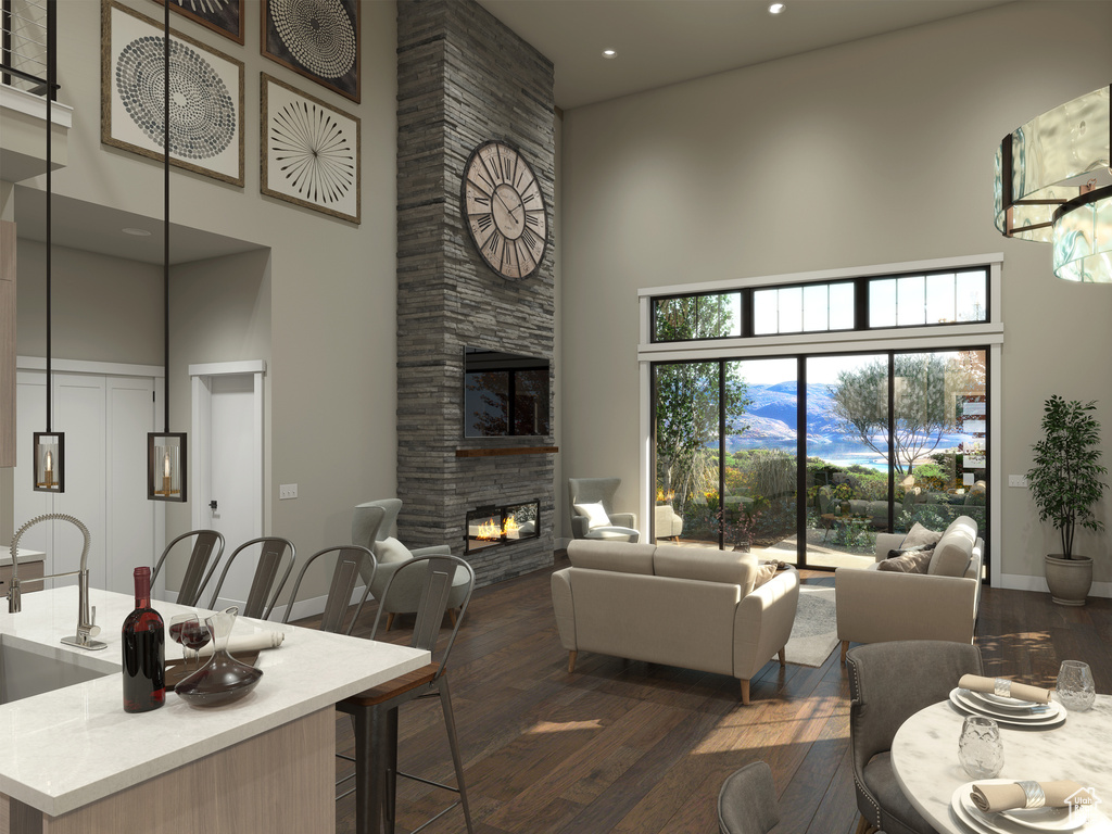 Living room with dark wood-type flooring, a towering ceiling, and a fireplace