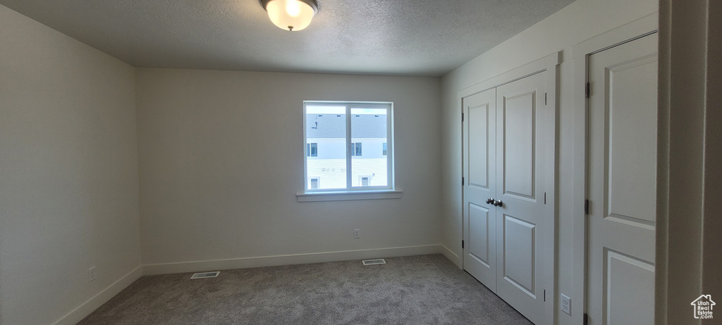 Unfurnished bedroom featuring carpet and a textured ceiling