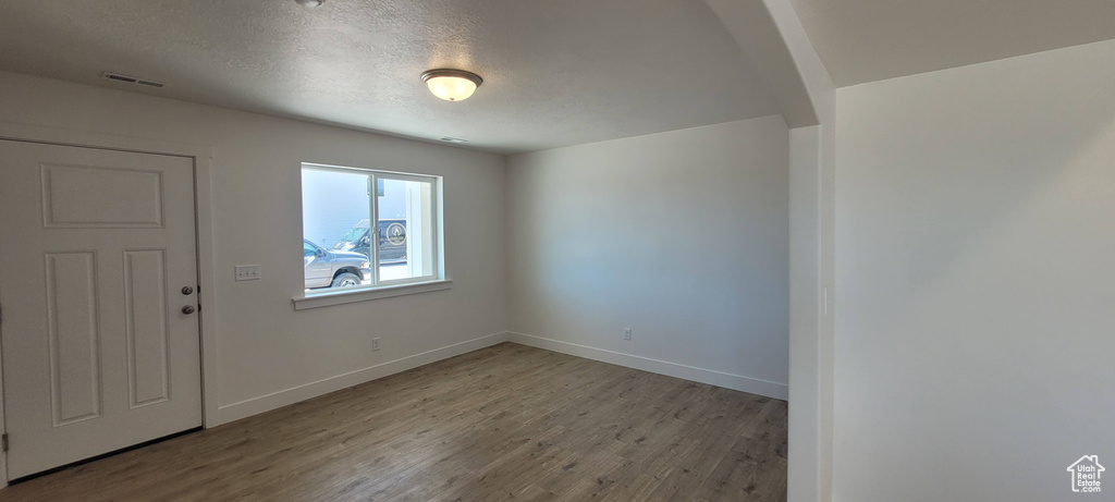 Spare room with a textured ceiling and wood-type flooring