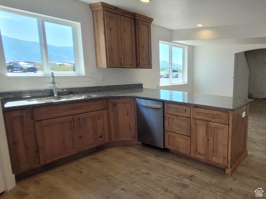 Kitchen with sink, light wood-type flooring, stainless steel dishwasher, and dark stone countertops