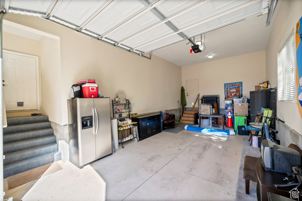 Garage featuring stainless steel fridge and a garage door opener