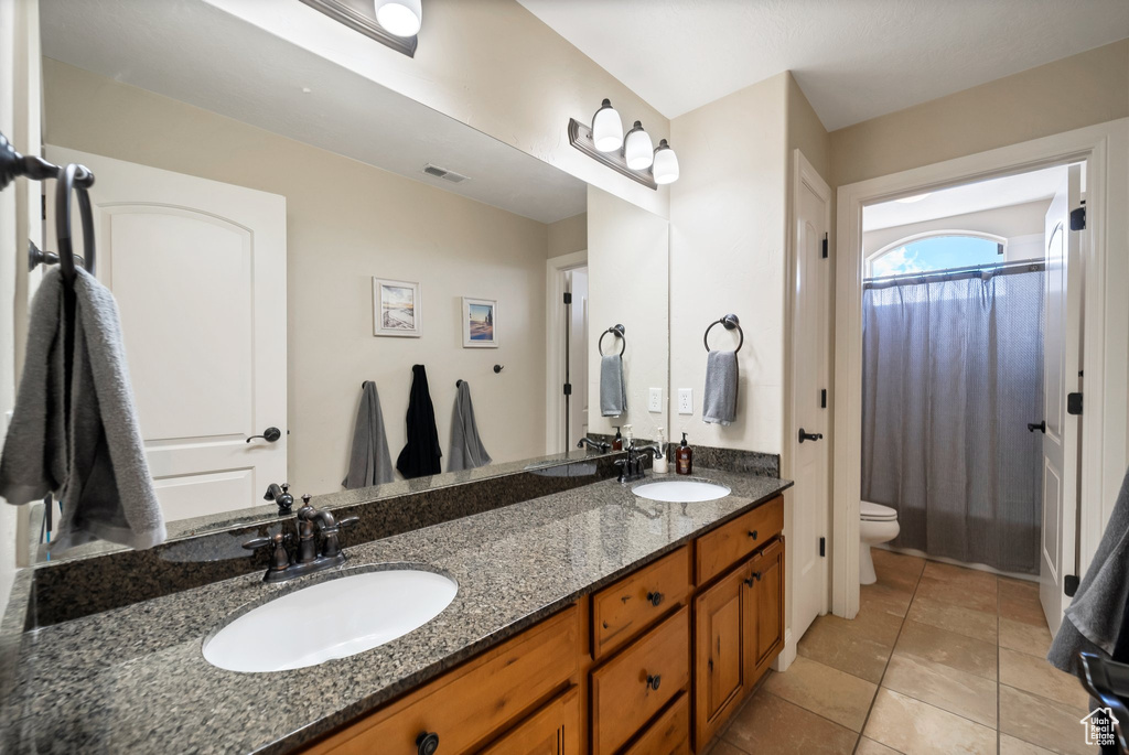 Bathroom with tile floors, double vanity, and toilet