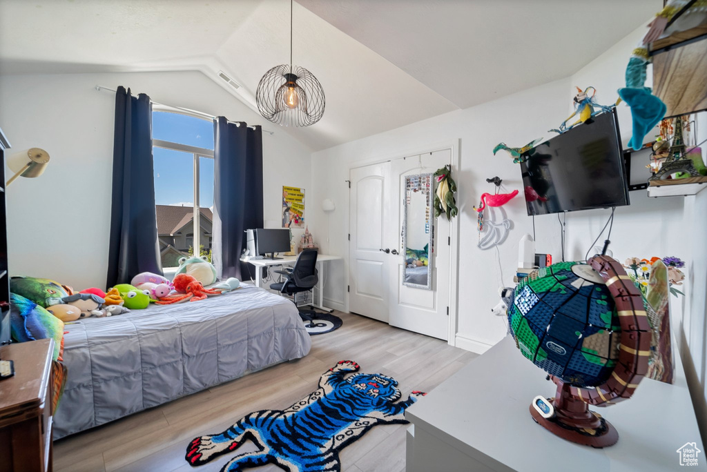 Bedroom with light hardwood / wood-style floors and vaulted ceiling